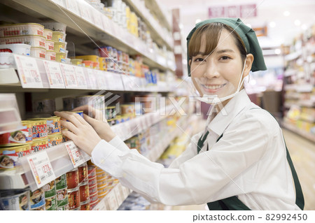 A female employee with a mouse shield who manages products at a supermarket A female employee with a mouse shield who manages products at a supermarket 82992450