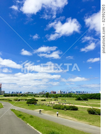Scenery of a riverbed with a spacious lawn and a promenade under the blue sky Yodogawa riverbed Moriguchi City Osaka Prefecture 82992903