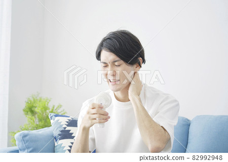 A man using a small fan in the room 82992948