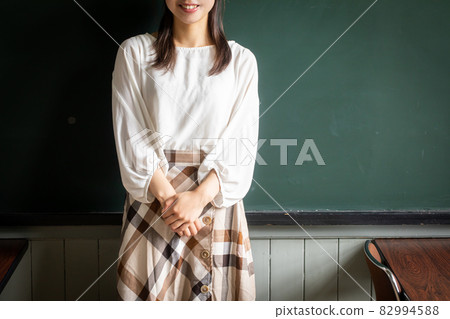 一個站在黑板前的女人,一個在黑板前微笑的學生 一個站在黑板前的女人,一個在黑板前微笑的學生 82994588