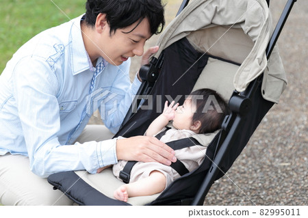 Daddy taking a walk with a 0 year old baby in a stroller 82995011