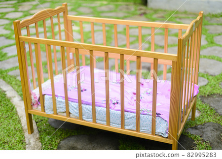 Baby crib with soft mattress and cozy sheets, stylish wooden finish on the crib. Baby crib with soft mattress and cozy sheets, stylish wooden finish on the crib. 82995283