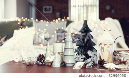 Christmas or New Year composition with various home decorations, different symbolic toys composed and ordered at coffee table with blurred Christmas lights background at sofa white cover. Family time Christmas or New Year composition with various home decorations, different symbolic toys composed and ordered at coffee table with blurred Christmas lights background at sofa white cover. Family time 82996068