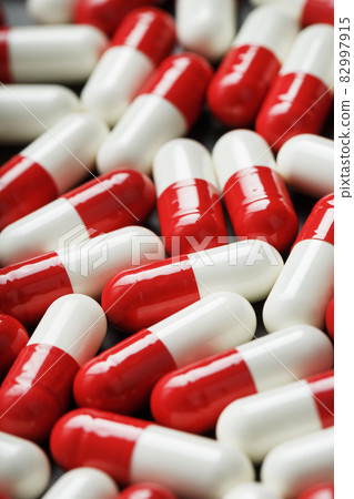 Medical medicinal Pills capsules are white and red in color as a background in full screen. 82997915