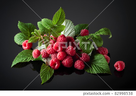Fresh raspberries with leaves on a black background. Fresh raspberries with leaves on a black background. 82998538