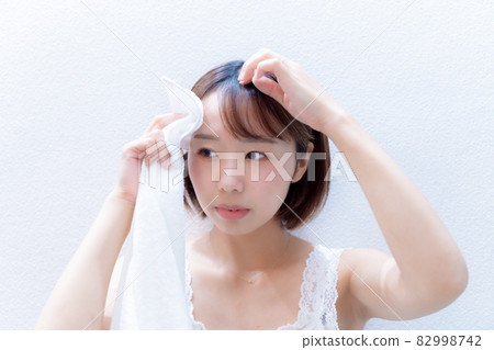 Woman wiping her forehead with a towel 82998742