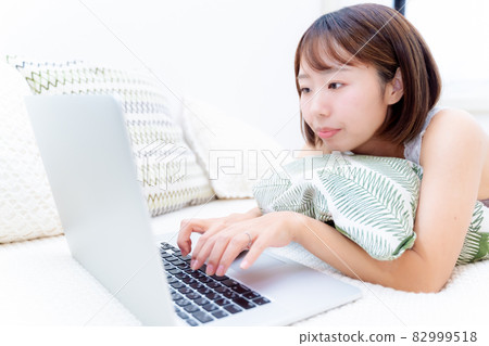 一個女人在床上睡覺時使用電腦 一個女人在床上睡覺時使用電腦 82999518