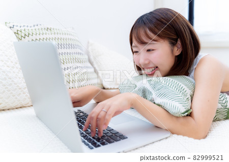 一個女人在床上開心地看著電腦 一個女人在床上開心地看著電腦 82999521