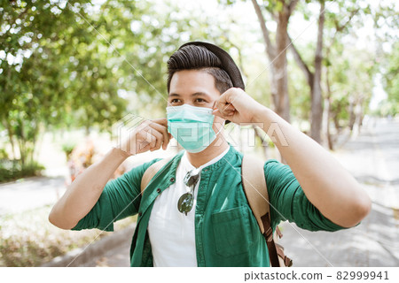 Coronavirus. Asian man putting on a medical disposable mask to avoid viruses. Coronavirus. Asian man putting on a medical disposable mask to avoid viruses. 82999941