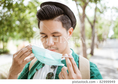 Coronavirus. Asian man putting on a medical disposable mask to avoid viruses. Coronavirus. Asian man putting on a medical disposable mask to avoid viruses. 82999949