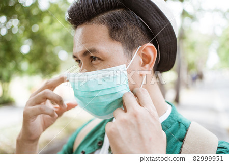 Coronavirus. Asian man putting on a medical disposable mask to avoid viruses. Coronavirus. Asian man putting on a medical disposable mask to avoid viruses. 82999951