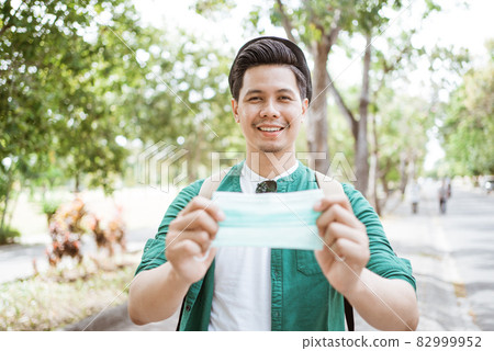 Coronavirus. Asian man putting on a medical disposable mask to avoid viruses. Coronavirus. Asian man putting on a medical disposable mask to avoid viruses. 82999952