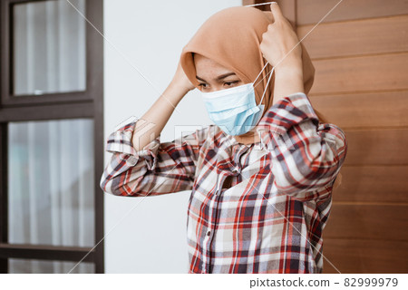 Coronavirus. Asian woman putting on a medical disposable mask to avoid viruses. Coronavirus. Asian woman putting on a medical disposable mask to avoid viruses. 82999979