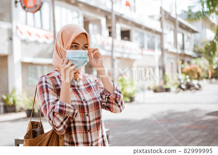 Coronavirus. Asian woman putting on a medical disposable mask to avoid viruses. 82999995