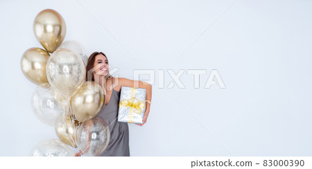 Photo of laughing girl hold large wrapped giftbox and many air balloons. Celebration. Advertisement Photo of laughing girl hold large wrapped giftbox and many air balloons. Celebration. Advertisement 83000390