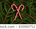 new year christmas red-white christmas candy lollipops on background of fir branches, christmas tree 83000752
