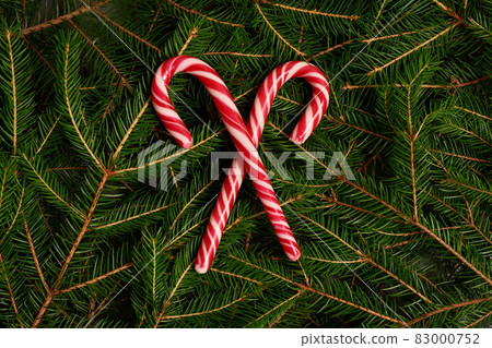 new year christmas red-white christmas candy lollipops on background of fir branches, christmas tree 83000752