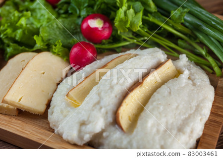 Mengrelian corn mamalica (ghomi) with cheese and various herb on wooden table. Georgian traditional food 83003461