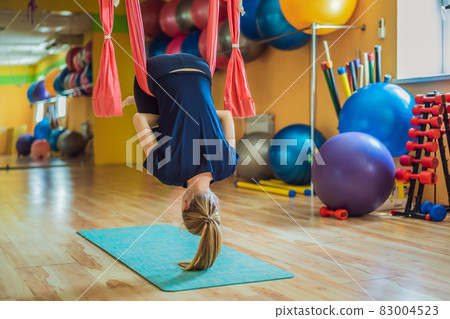 Young beautiful woman practicing aerial yoga in gym. Lifestyle 83004523