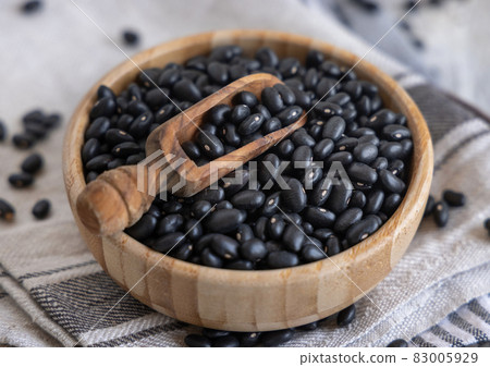Wooden bowl full of dried black beans with a wooden spoon close up Wooden bowl full of dried black beans with a wooden spoon close up 83005929