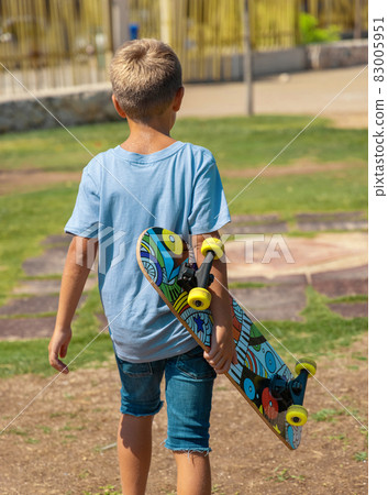 Preschooler boy keep a skateboard in hands in park Preschooler boy keep a skateboard in hands in park 83005951
