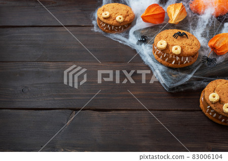 Cookies with cream paste in the shape of monsters for Halloween celebration. Funny homemade faces made of oatmeal cookies and boiled condensed milk. copy space Cookies with cream paste in the shape of monsters for Halloween celebration. Funny homemade faces made of oatmeal cookies and boiled condensed milk. copy space 83006104