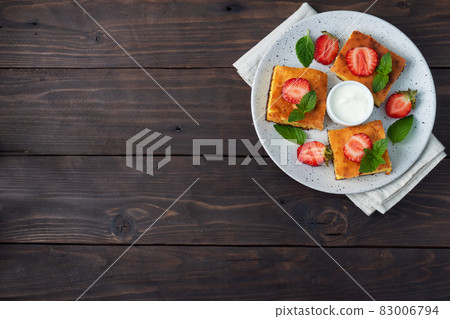 Cottage cheese casserole with strawberries and mint. Delicious homemade dessert made of curd and fresh berries with cream. dark wooden background, copy space. Cottage cheese casserole with strawberries and mint. Delicious homemade dessert made of curd and fresh berries with cream. dark wooden background, copy space. 83006794