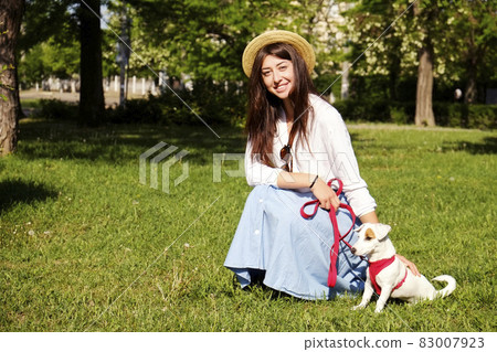 Attractive hipster young woman went for a walk in the park, playing with cute jack russell terrier puppy on clear sunny day. 83007923
