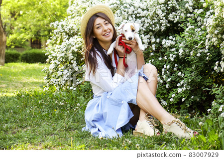 Attractive hipster young woman went for a walk in the park, playing with cute jack russell terrier puppy on clear sunny day. 83007929