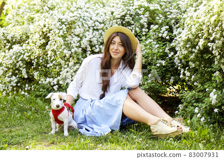 Attractive hipster young woman went for a walk in the park, playing with cute jack russell terrier puppy on clear sunny day. 83007931