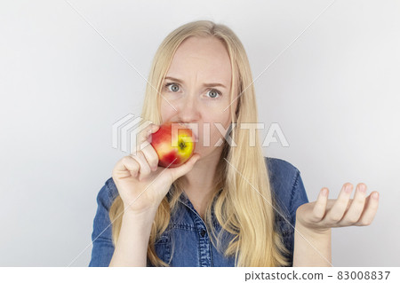 Loss of taste. A girl in front of a mirror eats a chocolate bar or an apple and realizes that she does not feel taste. Diagnostics of covid-19. Symptoms of the coronavirus. Self-test on sars-cov-2 83008837