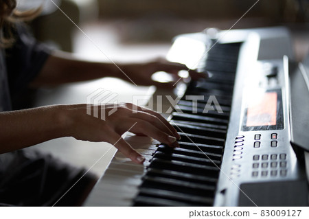 The musician's hands on the synthesizer. A cropped image of a person playing a synthesizer. Side view. High quality photo 83009127