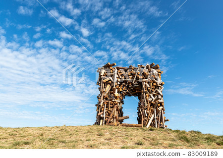 Big square wooden arc of cut round tree logs against vibrant blue sky and bright sun on warm sunny day. Natural material park garden decoration object Big square wooden arc of cut round tree logs against vibrant blue sky and bright sun on warm sunny day. Natural material park garden decoration object 83009189
