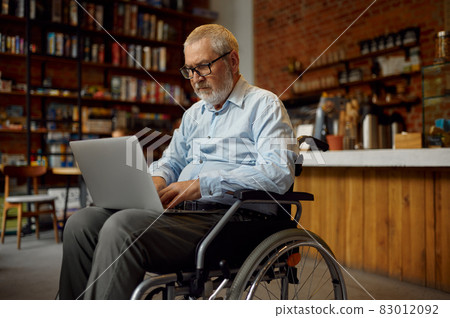 Adult disabled man in wheelchair using laptop Adult disabled man in wheelchair using laptop 83012092