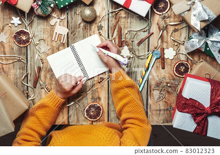 Woman hands with pen and notepad writing letter to santa claus o 83012323