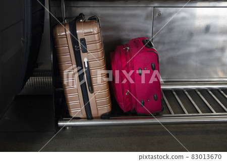 Traveler and tourism suitcases stacked in the luggage compartment of a train 83013670