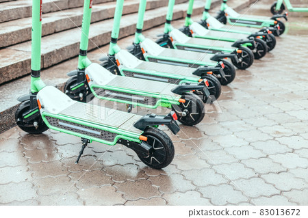 Rental modern electric scooter with rain drops at the street in urban city. Zero emission green eco energy Rental modern electric scooter with rain drops at the street in urban city. Zero emission green eco energy 83013672