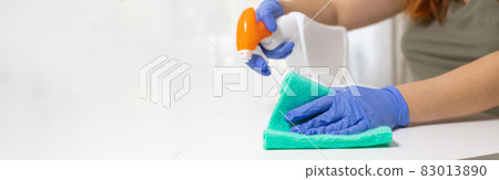 Woman cleaning table with green color disinfectant spray and yellow towel. COVID-19 prevention sanitizing inside 83013890