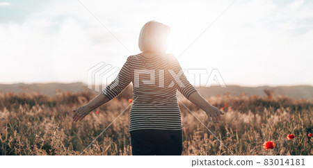 Hiking woman standing in field and watching horizon with beautiful sky at sunset. Beautiful landscape, freedom, the unity of human and nature Hiking woman standing in field and watching horizon with beautiful sky at sunset. Beautiful landscape, freedom, the unity of human and nature 83014181
