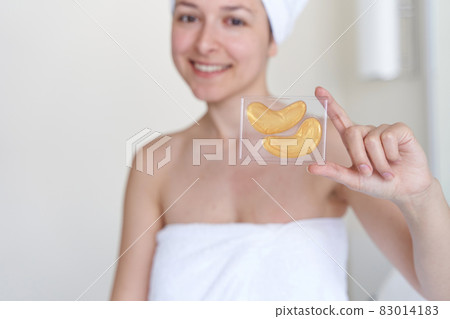 After a shower, the girl is wrapped in a towel and wears cosmetic patches for the skin under the eyes. Cosmetic procedures at home After a shower, the girl is wrapped in a towel and wears cosmetic patches for the skin under the eyes. Cosmetic procedures at home 83014183