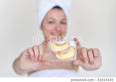 After a shower, the girl is wrapped in a towel and wears cosmetic patches for the skin under the eyes. Cosmetic procedures at home After a shower, the girl is wrapped in a towel and wears cosmetic patches for the skin under the eyes. Cosmetic procedures at home 83014184