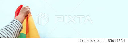 Young person hand with a colorful rainbow flag on blue background. LGBT equal rights movement and gender equality concept Young person hand with a colorful rainbow flag on blue background. LGBT equal rights movement and gender equality concept 83014234