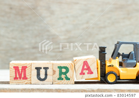 Toy forklift hold letter block a to complete word mura on wood background 83014597