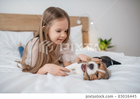 A cute girl playing with her puppy and looking happy 83016445