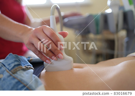 Ultrasound scanner in hands of doctor examines woman pelvis Ultrasound scanner in hands of doctor examines woman pelvis 83016679
