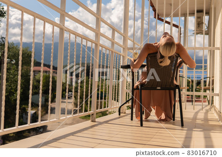 The girl sits on the balcony of the mountains and the blue sky on the background of beauty people beautiful female, adult person pretty beauty leisure house. Inspiration city relaxing, vacation hotel The girl sits on the balcony of the mountains and the blue sky on the background of beauty people beautiful female, adult person pretty beauty leisure house. Inspiration city relaxing, vacation hotel 83016710