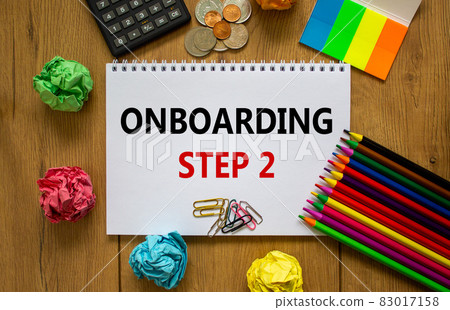 Onboarding symbol. White note with a word 'onboarding step 2' on beautiful wooden table, colored paper, colored pencils, paper clips, coins and calculator. Business and onboarding step 2 concept. 83017158
