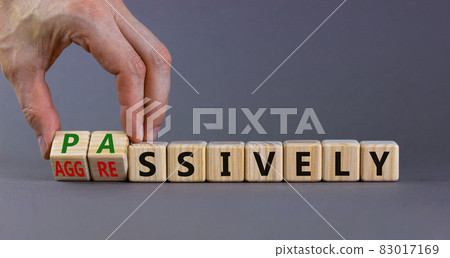Passively or aggressively symbol. Businessman turns cubes and changes the word passively to aggressively. Psychological and passively or aggressively concept. Beautiful grey background, copy space. Passively or aggressively symbol. Businessman turns cubes and changes the word passively to aggressively. Psychological and passively or aggressively concept. Beautiful grey background, copy space. 83017169