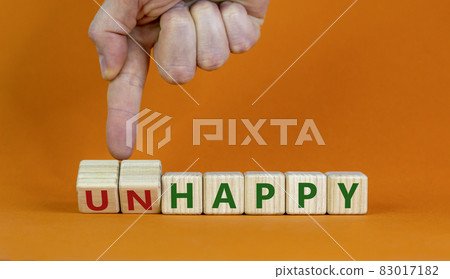 Be happy, do not unhappy symbol. Businessman turns wooden cubes and changes the word 'unhappy' to 'happy'. Beautiful orange background. Business, happy or unhappy concept. Copy space. 83017182