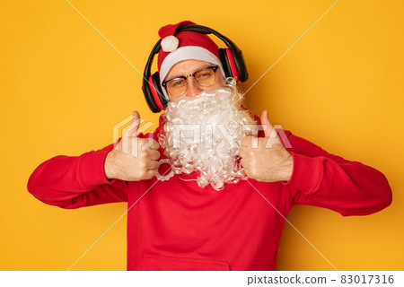 DJ Santa Claus in headphones. Christmas songs and music. yellow background. DJ Santa Claus in headphones. Christmas songs and music. yellow background. 83017316